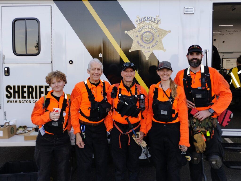 Five YCSAR volunteers in orange search gear at a mission command vehicle